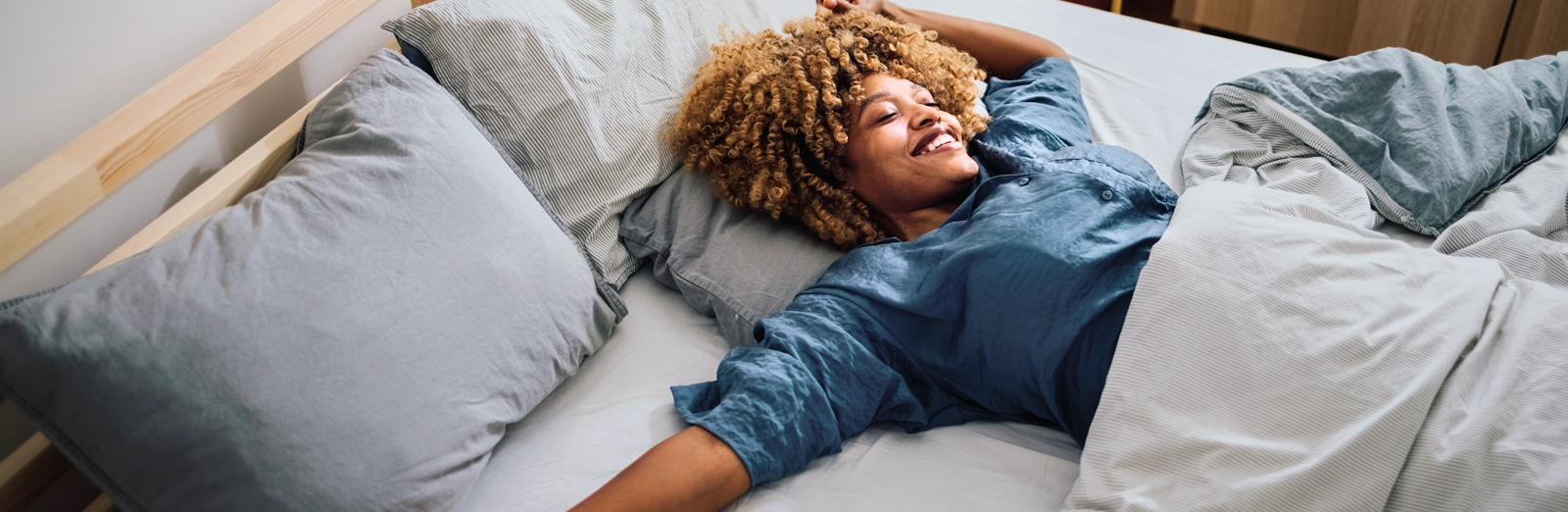 woman-smiling-in-bed-1600x522.webp