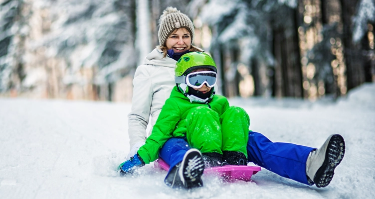 child-wearing-goggles-while-sledding-with-mom-752x400.webp