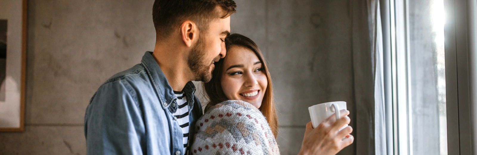 couple-smiling-holding-mug-1600x522.webp
