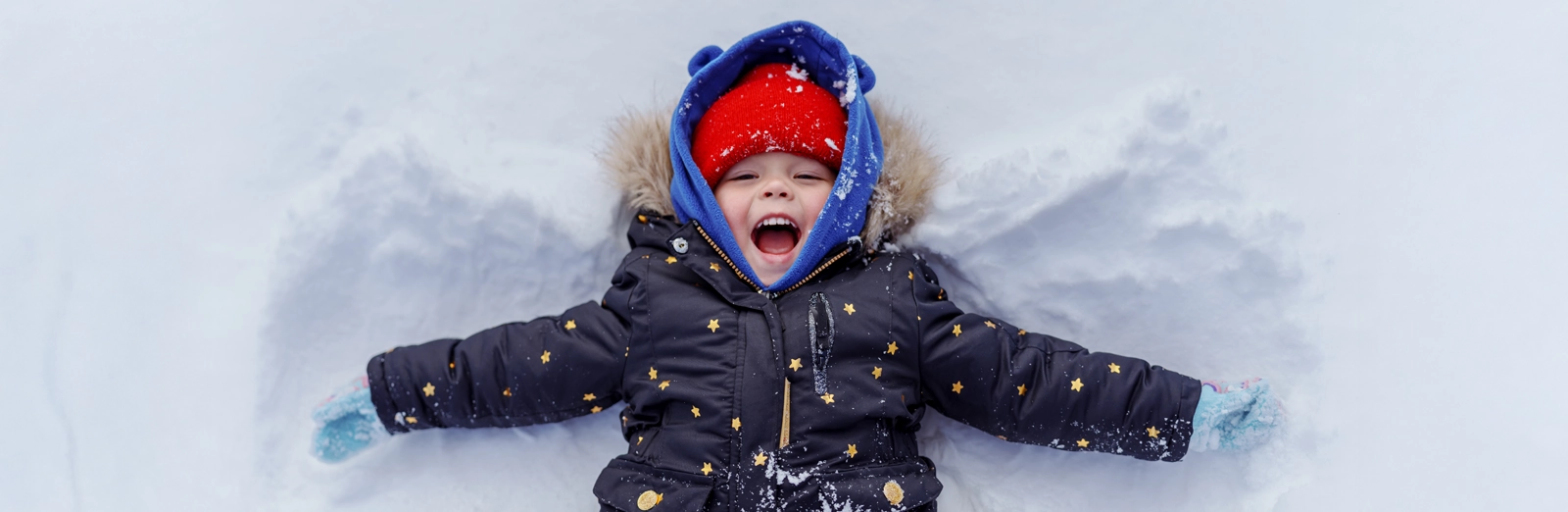 young-boy-laying-in-the-snow-1600x522.webp
